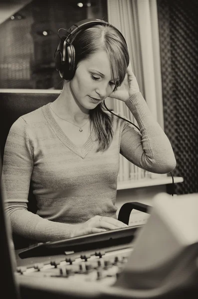 Portrait of female dj working in front of a microphone on the radio. Black