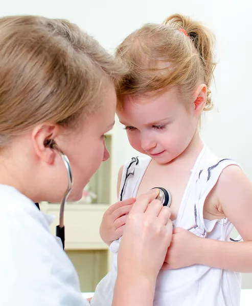 Female doctor examining little girl with stethoscope