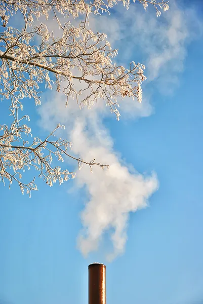 Factory pipe with smoke over blue sky background