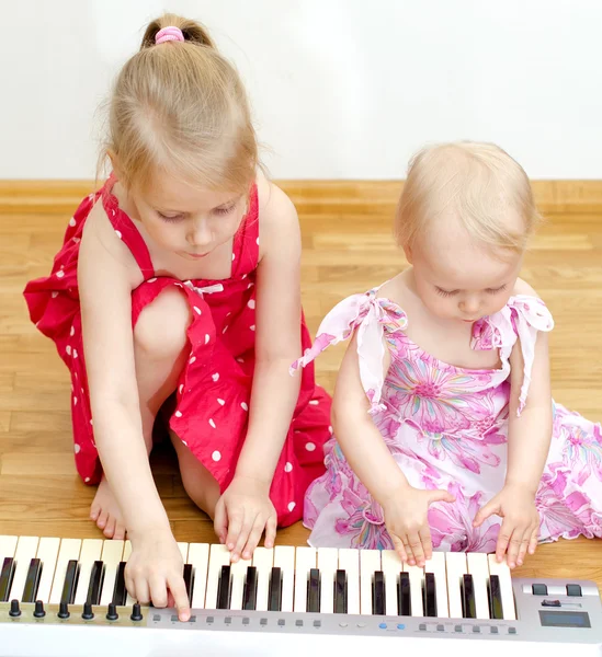 Two little girls playing the piano
