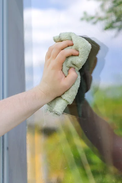 Male hand with rag washing window outdoors