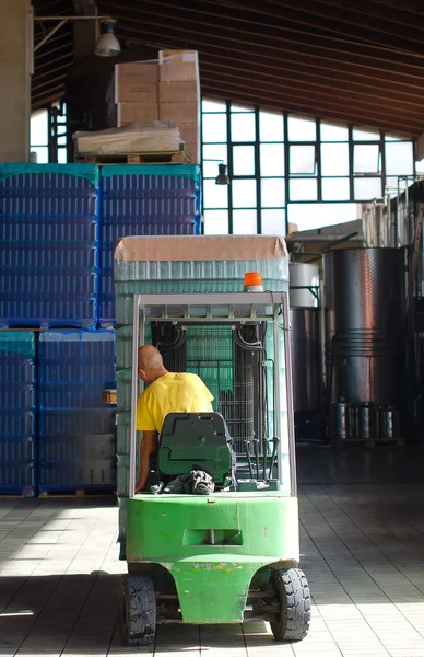 Warehouse worker loading wine boxes by forklift