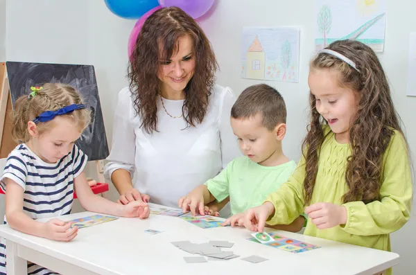 Teacher plays with children in kindergarten.