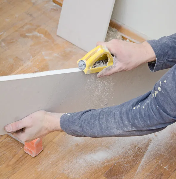 Male hand grinding gypsum for smoothing surface