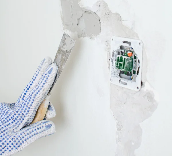 Female hand repairs wall with spackling paste