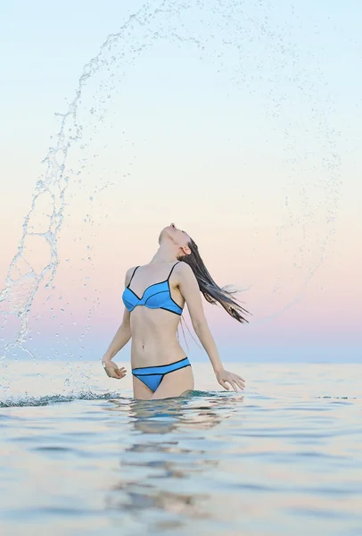 Woman in water waving hair.