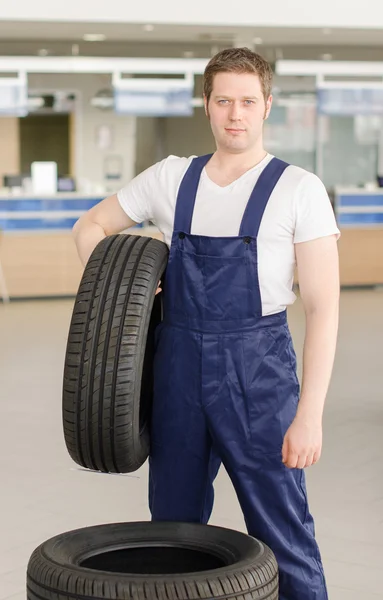 Young mechanic with tire in service center.