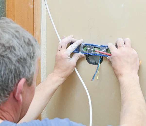Certified electrician installing socket for light switch.