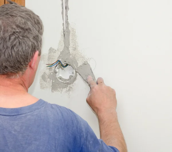 Man repairs wall with spackling paste.