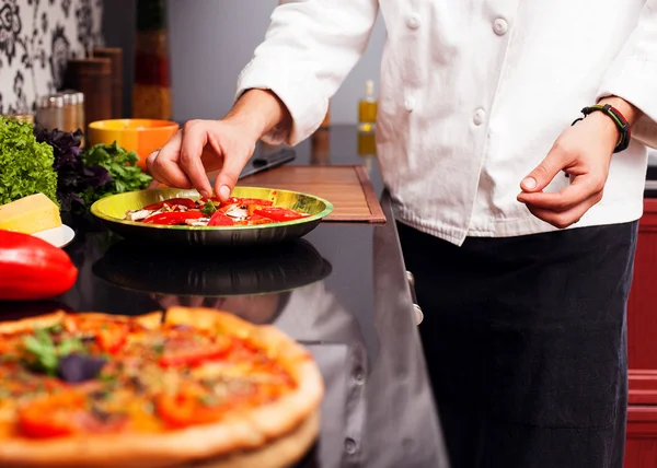 Close-up of a male chef preparing a pizza in a kitchen