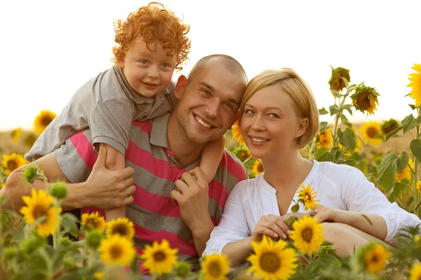 Happy family having fun in the field of sunflowers. Father hugs his son.