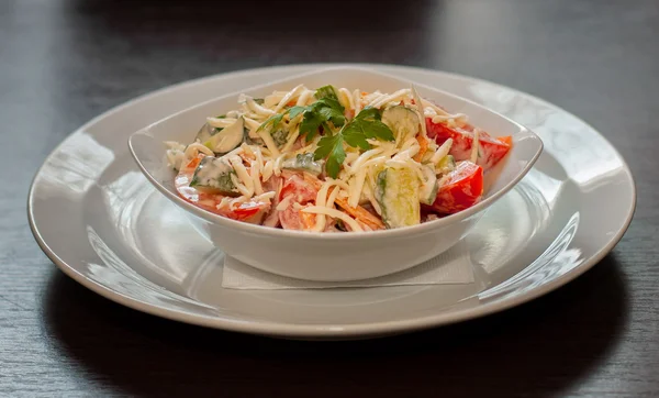 Salad from cucumbers and tomato with grated cheese and sour cream