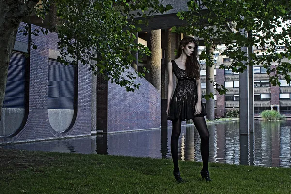 Young fashion model outdoor shoot posing wearing short black dress