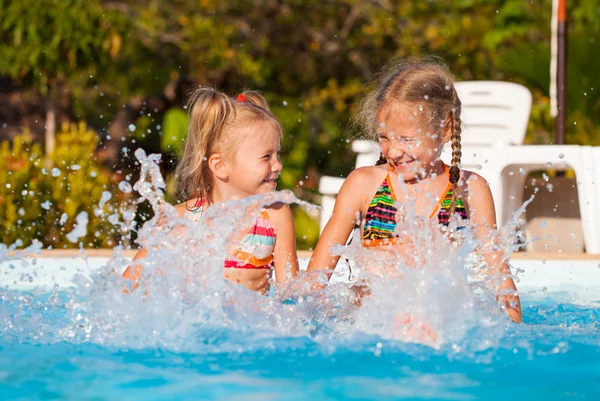 Two happy little girls splashing around in the pool