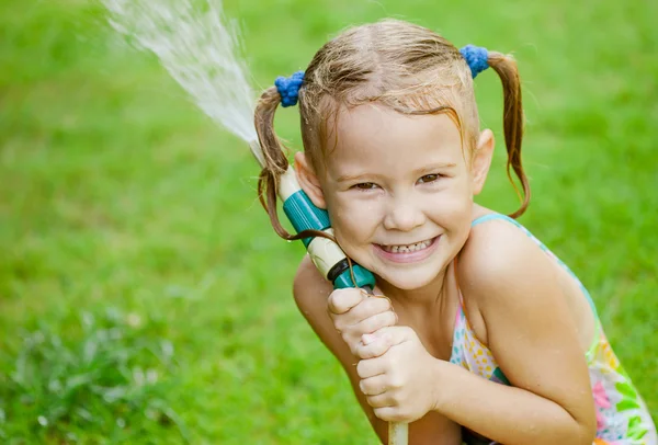 Happy girl pours water from a hose