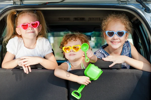 Two little girls and boy sitting in the car