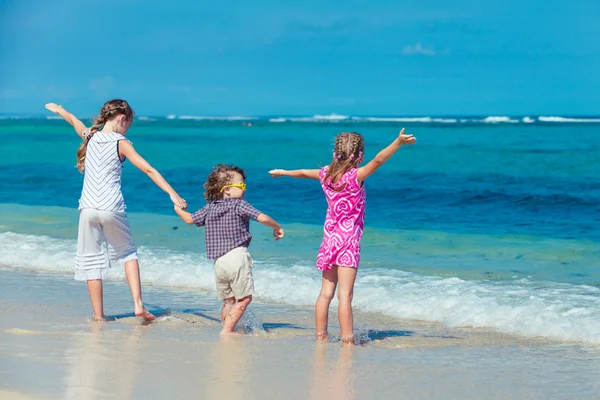 Three children standing on the beach and pulled up his hands