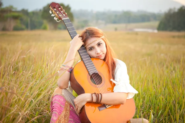 Hippie girl playing guitar on grass