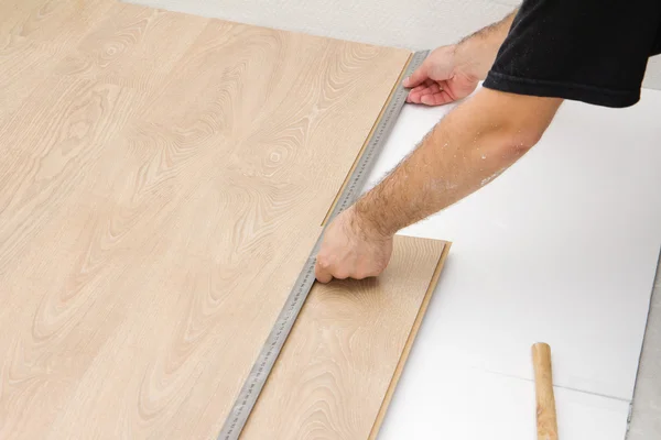 Carpenter worker installing laminate board during flooring work