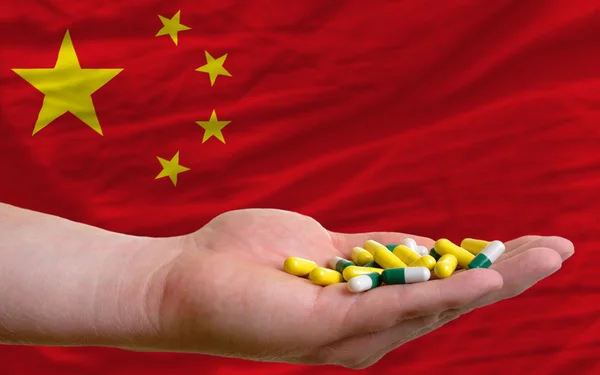 Holding pills in hand in front of china national flag