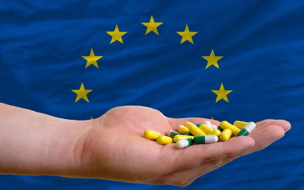 Holding pills in hand in front of europe national flag