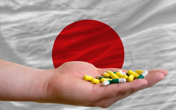 Holding pills in hand in front of japan national flag