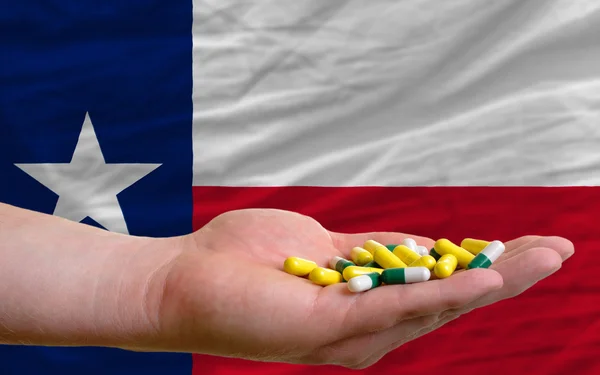 Holding pills in hand in front of texas us state flag