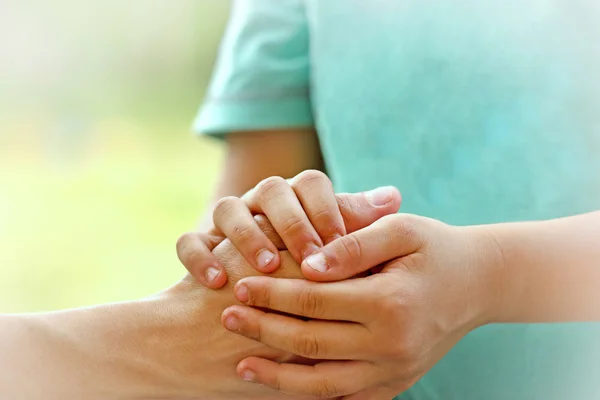 Son holds the hand of his mother