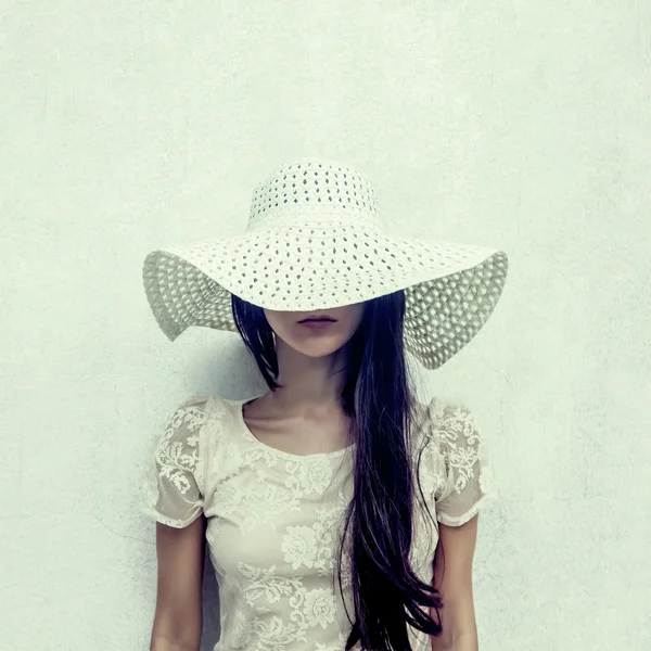 Fashion portrait of a sensual girl in a hat against the wall