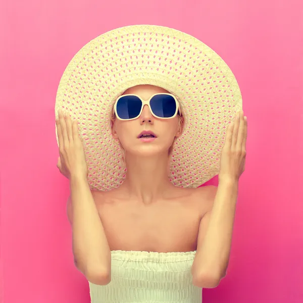 Portrait of a girl in a hat on a pink background