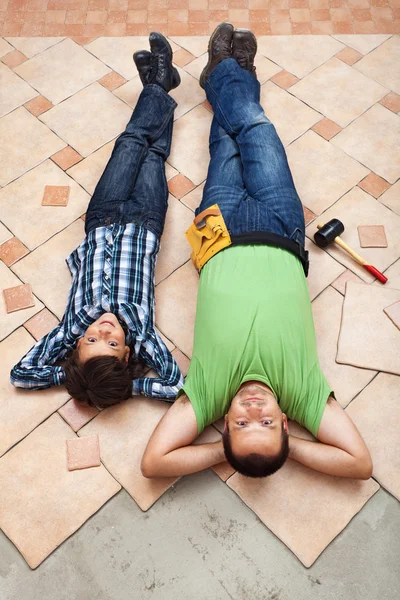 Father and son resting while laying floor tiling