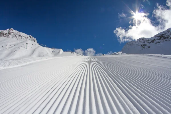 Fresh snow groomer tracks on a ski piste