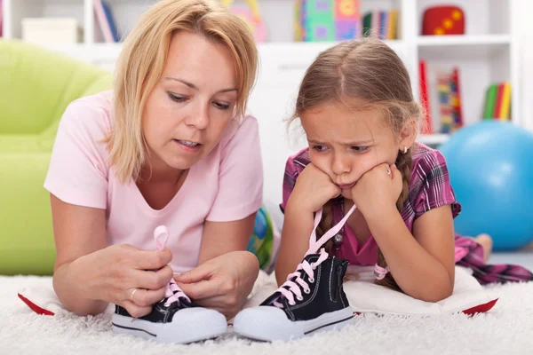 Mother teaching little girl to tie her shoes