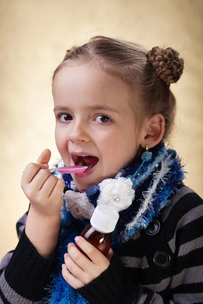 Little girl taking cough medicine syrup