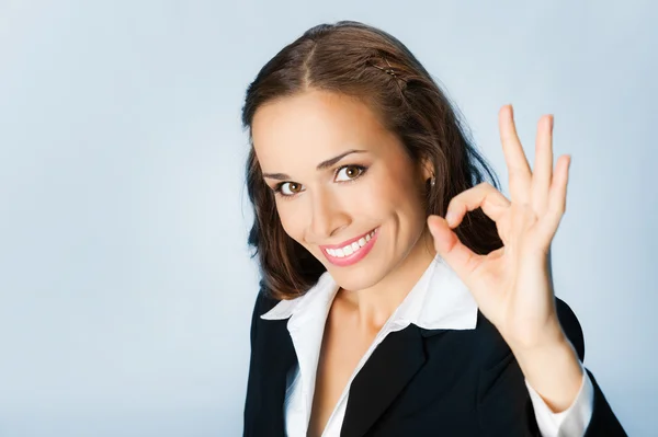 Happy business woman with okay gesture, over blue