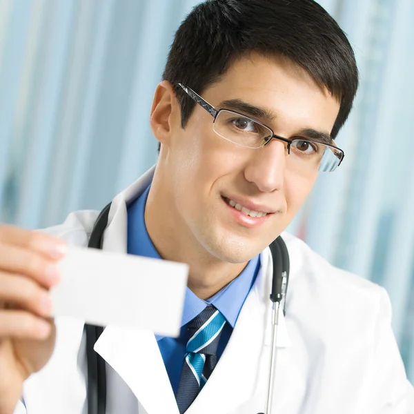Doctor showing business card, at office