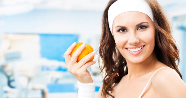 Woman with orange, at fitness center