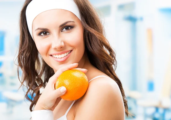 Woman with orange, at fitness center — Stock Photo #26545833