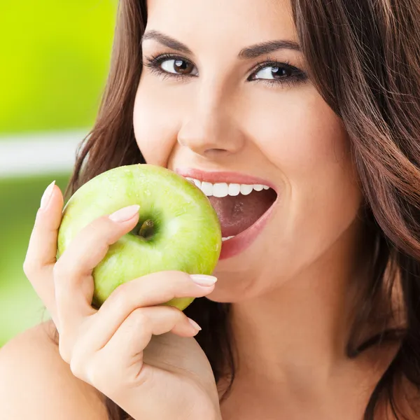 Young woman eating apple, outdoors