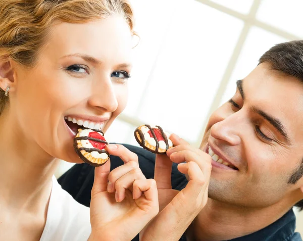 Cheerful couple eating cookies