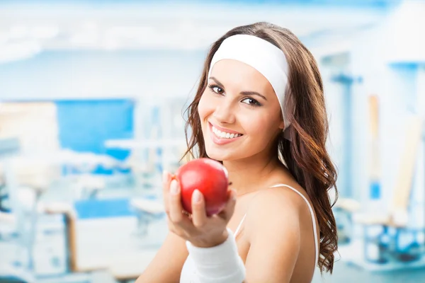 Woman with apple, at fitness center