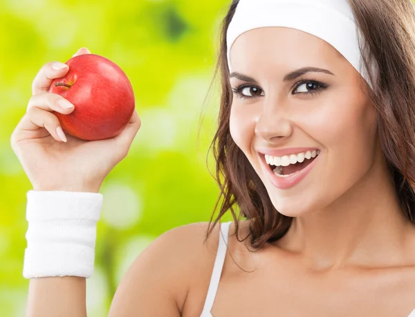 Woman in fitness wear with apple, outdoors