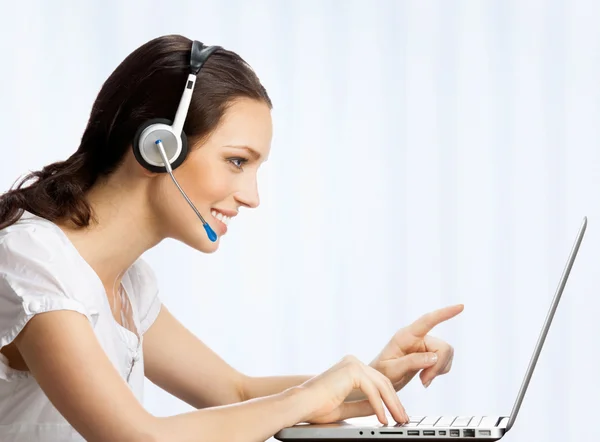 Phone operator in headset with laptop, at office