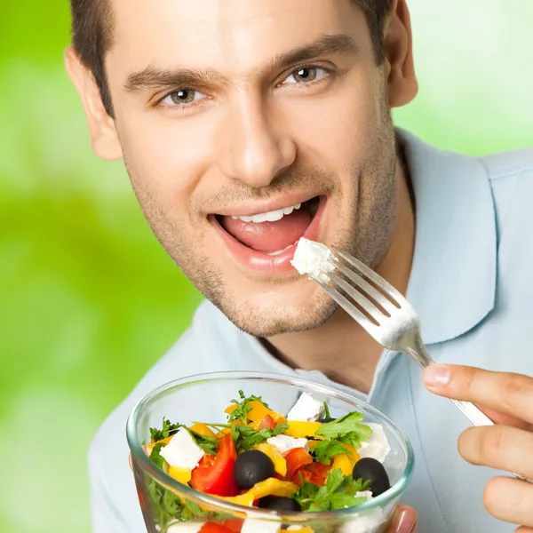 Portrait of young happy man eating salad