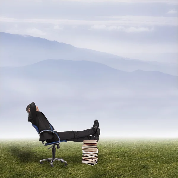 Businessman in office chair in field with mountains