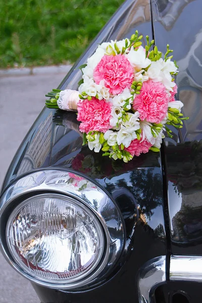 Bridal bouquet lying on a black car