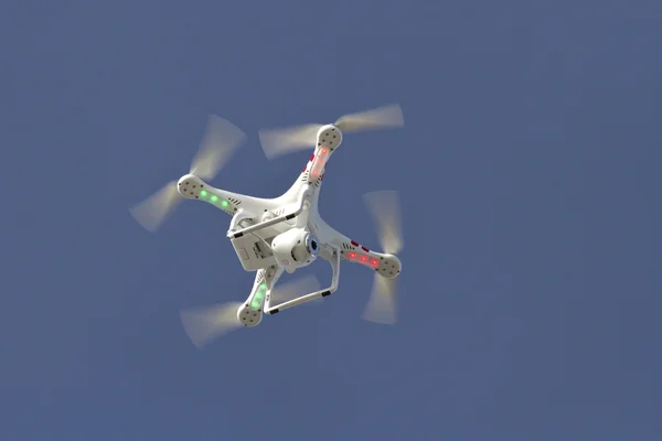 Small unmanned helicopter with a camera floating in the blue sky