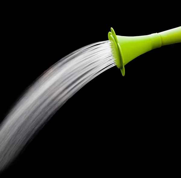 Green watering can pouring water with slow speed shutter isolate