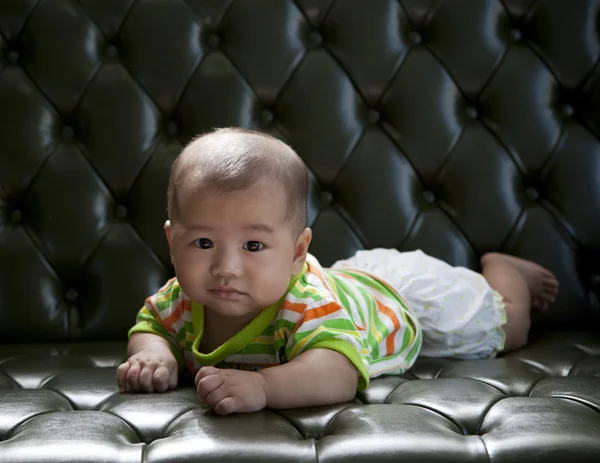Baby lying on sofa bed with eyes contact to camera