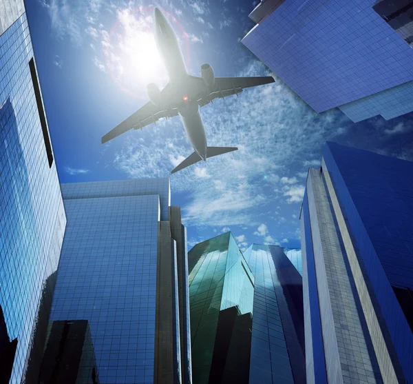 Passenger plane flying over modern office building against blue sky white cloud seem city life and air transport business scene